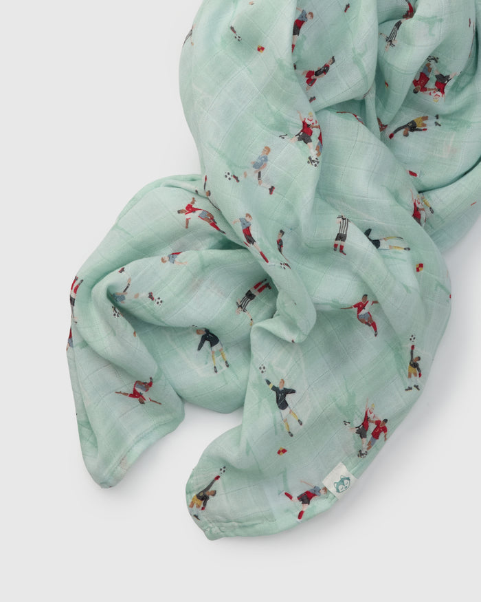 Light blue muslin swaddle  with small soccer printed designs on a white background