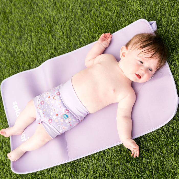 Child wearing reusable swim diaper in lilac and floral themed print. Front.
