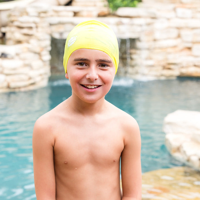 Kid wearing yellow silicone swim cap, poolside.