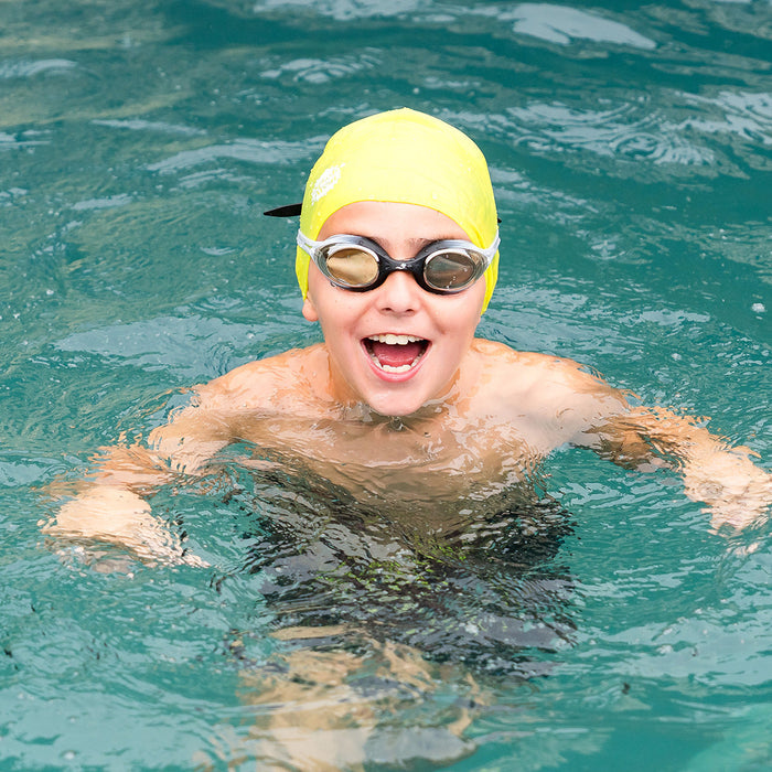 Kid swimming, wearing yellow silicone swim cap.