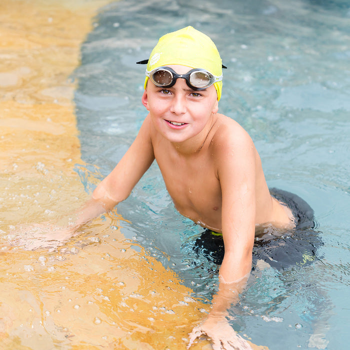 Kid swimming, wearing yellow silicone swim cap.
