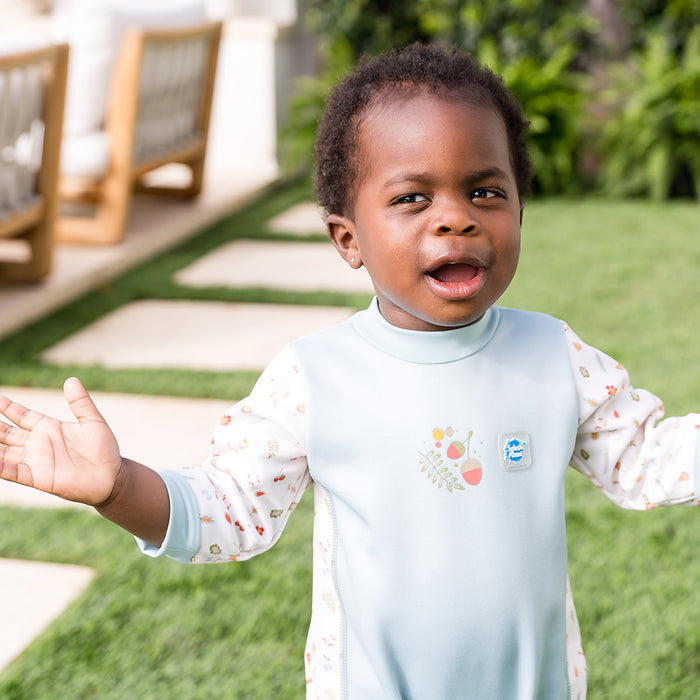 Child wearing acorns themed baby wetsuit in white and light blue.