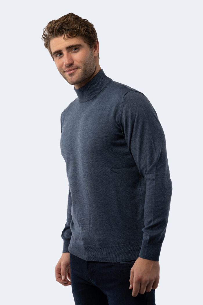 Man wearing a dark blue mock neck sweater against a white background