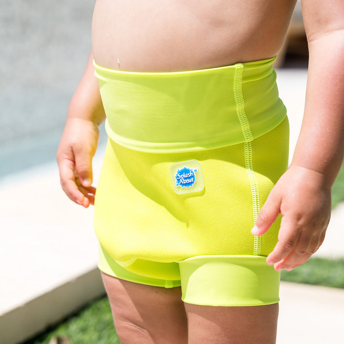 Close up of little one wearing neoprene swim diaper in bright lime green, front.
