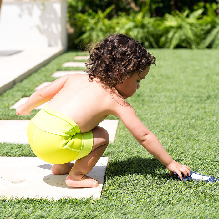 Little one swimming in neoprene swim diaper in bright lime green.