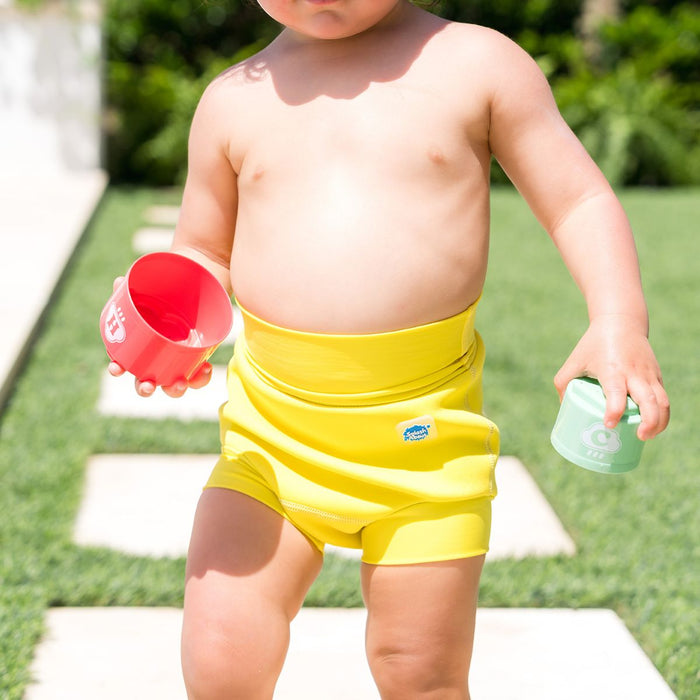 Close up of little one wearing neoprene swim diaper in bright yellow, front.