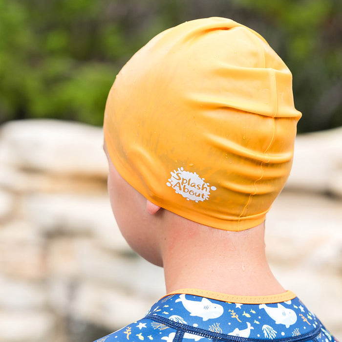 Close-up of kid wearing orange silicone swim cap, back.