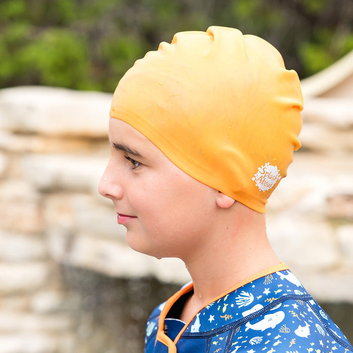Close-up of kid wearing orange silicone swim cap, side.