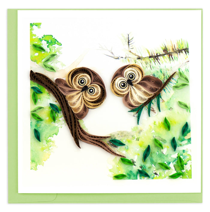 A greeting card with a 3D quilled design depicting two owls on a branch, surrounded by greenery.