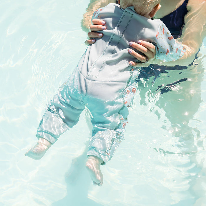 Child wearing otters themed baby wetsuit in light blue.