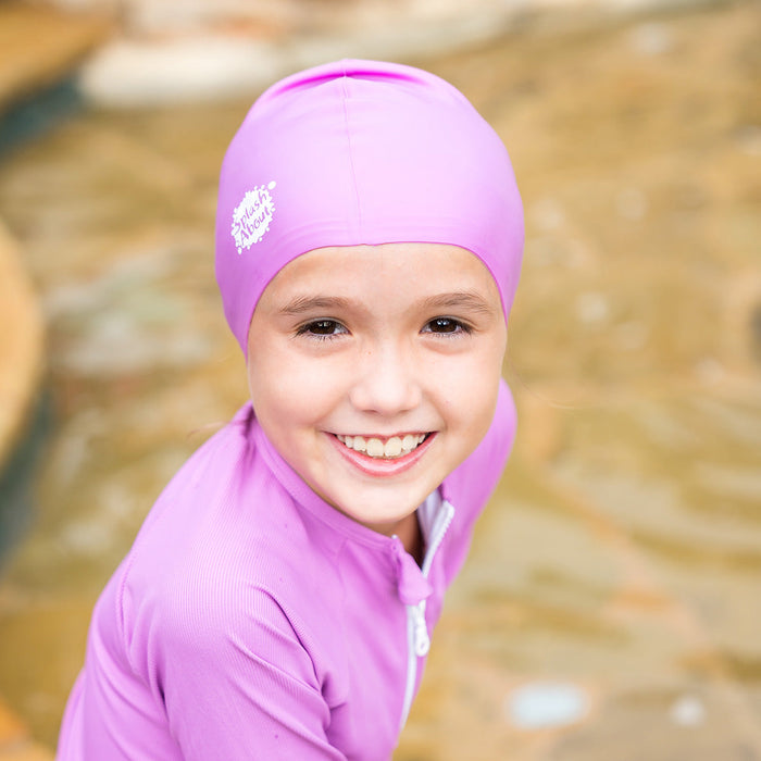 Close-up of kid wearing purple silicone swim cap, front.