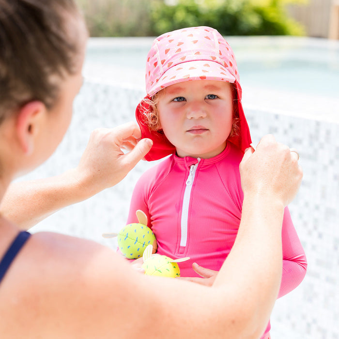 Little one wearing legionnaire style sun hat in pink and red, with strawberries themed print panel.