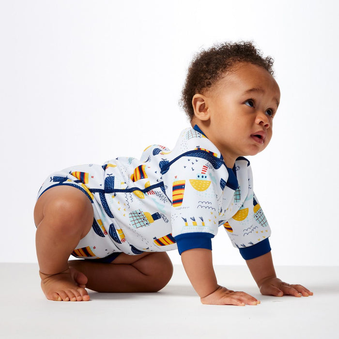 Lifestyle image of child wearing a baby wetsuit with built in swim diaper in white with navy trims and boats themed print. Side.