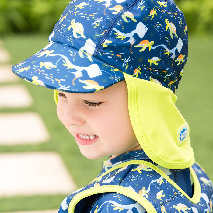 Little one wearing legionnaire style sun hat in navy and lime, with turtles and mantarays themed print panel.