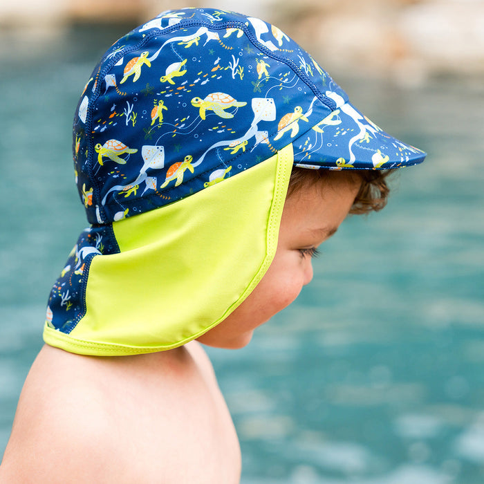 Little one wearing legionnaire style sun hat in navy and lime, with turtles and mantarays themed print panel.
