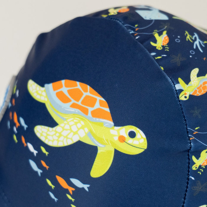 Baby swim hat in navy featuring turtles themed print.