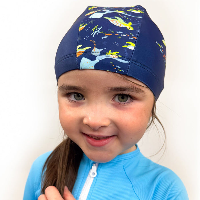 Child wearing baby swim hat in navy featuring turtles themed print.
