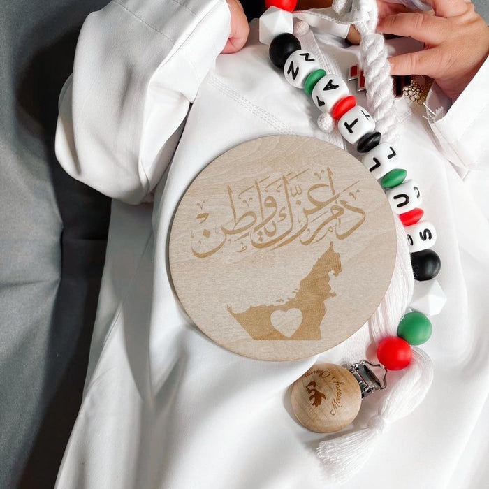 A close-up of a BABY wearing a white robe, CELEBRATING UAE NATIONAL DAY